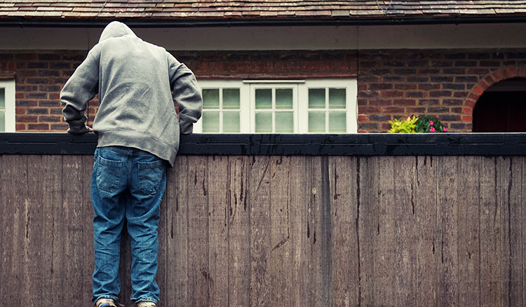 Burglar climbing over a fence